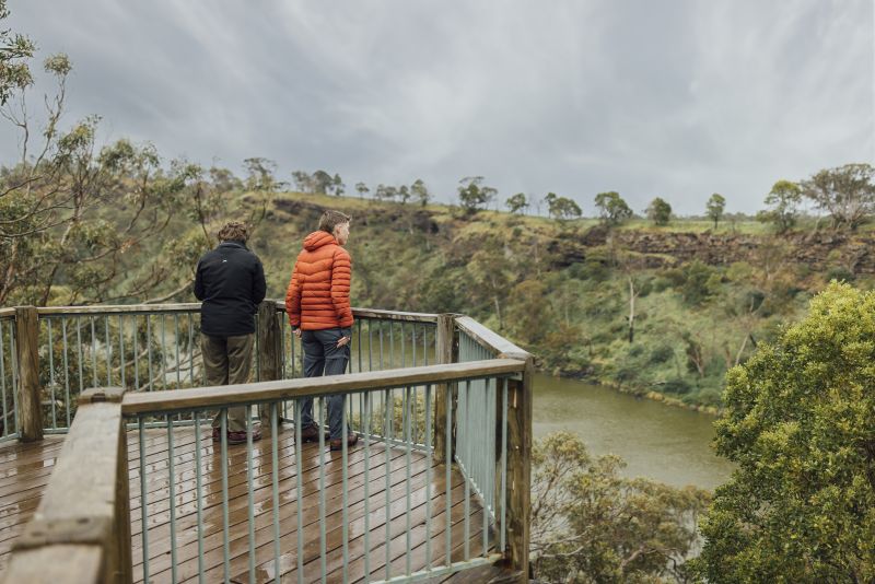 People on a look out looking onto australian bush land and a water body