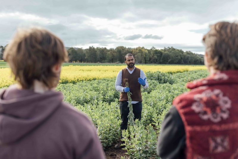 a man talking to two people standing in a field